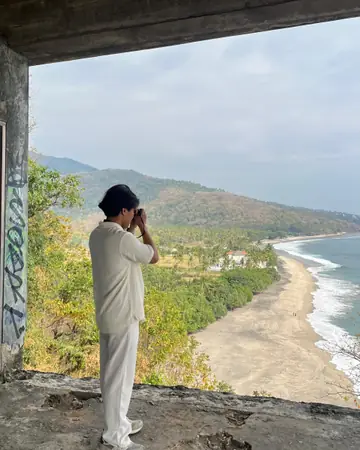 Naqiudin photographing a beach from a hilltop